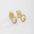 BR-01583 BRINCO BANHADO A OURO 18K EM FORMATO DE LETRA CRAVEJADO EM ZIRCÔNIAS